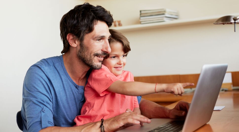 Ein Vater schaut mit seinem Sohn auf den Laptop