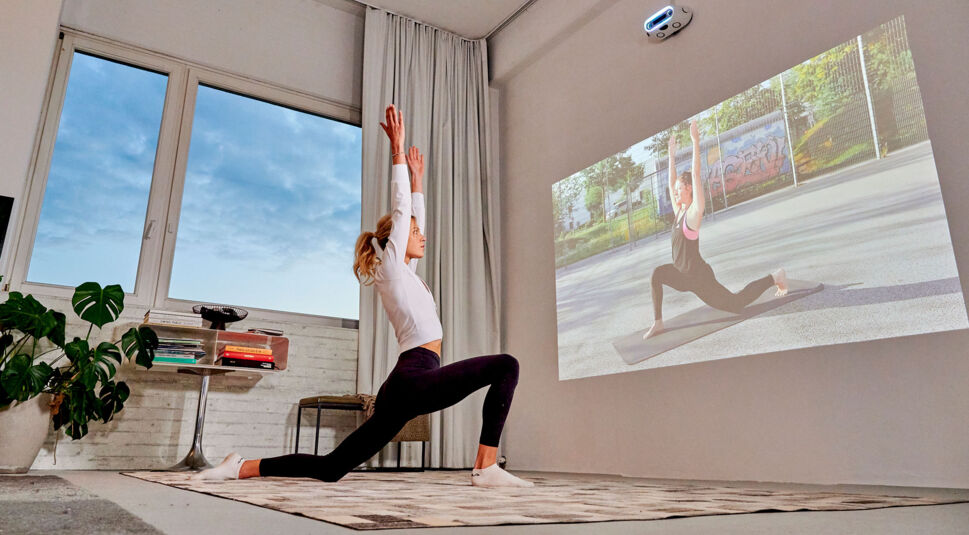 Eine Frau macht eine Yoga-Übung zuhause, indem sie ein virtuelles Workout ansieht.