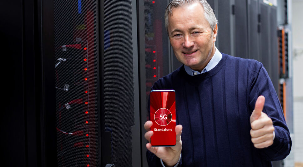 Vodafone Deutschland CEO Hannes Ametsreiter hält ein Smartphone, auf dessen Display "5G Standalone" zu sehen ist.