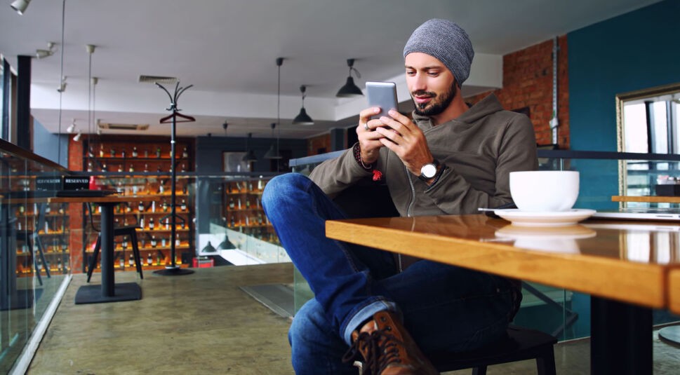 Mann nutzt Smartphone im Café