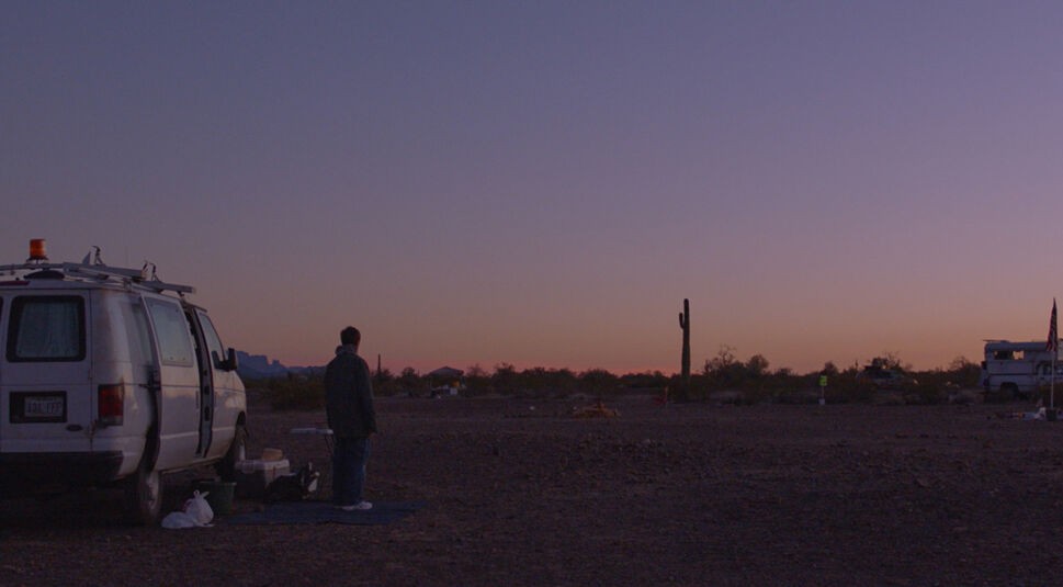 Fern (Frances Dormand) steht neben einem Campervan und blickt auf eine verlassene Landschaft gen Horizont.