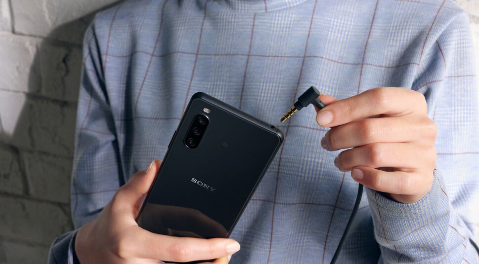 Eine Frau schließt Kopfhörer an das Sony Xperia 10 III 5G an.