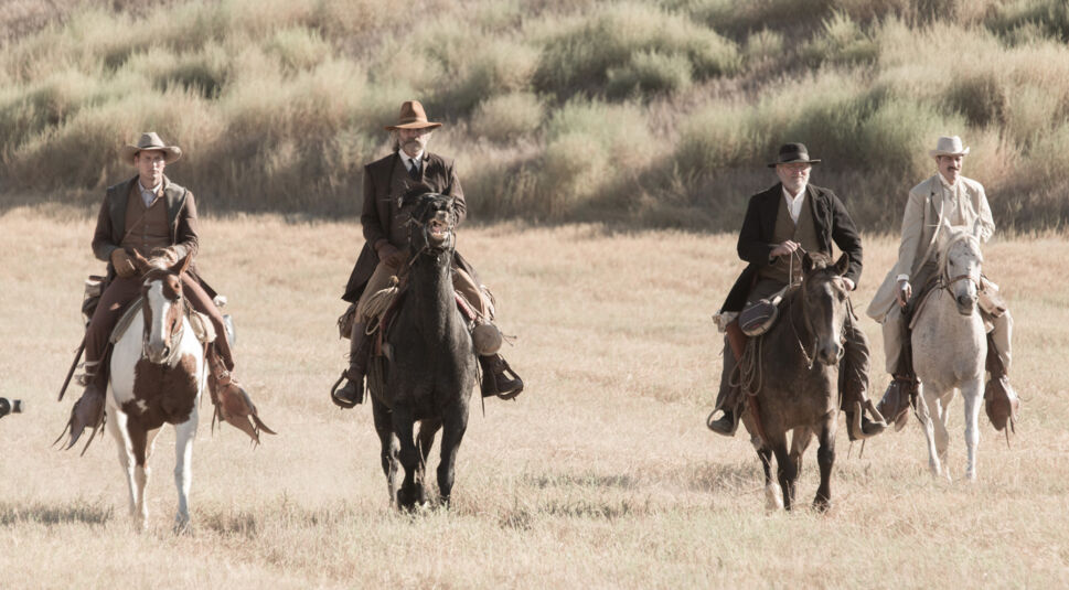 Vier Cowboys reiten durch die Prärie