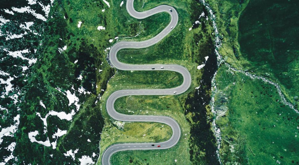 Eine Luftnahme zeigt, wie Autos auf einer Bergstraße entlang fahren.