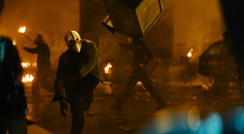 Menschen mit einer Schnabelmaske randalieren im Film "Major Grom: Der Pestdoktor" auf einer Straße.