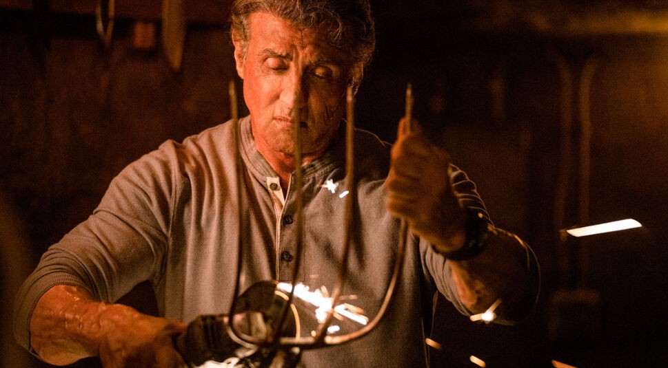 Rambo (Sylvester Stallone) schleift eine Mistgabel.