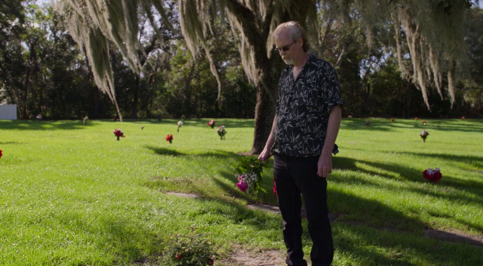 Steve Ross steht am Grab seines Vaters Bob Ross in der neuen Netflix-Doku „Bob Ross: Glückliche Unfälle, Betrug und Gier“