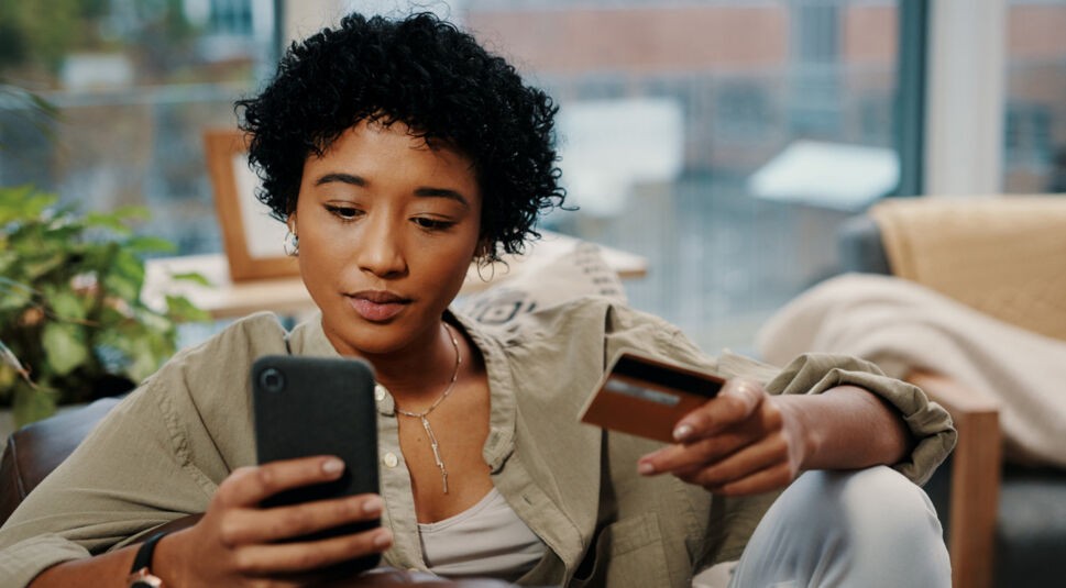 Frau hält Kreditkarte und Smartphone in der Hand