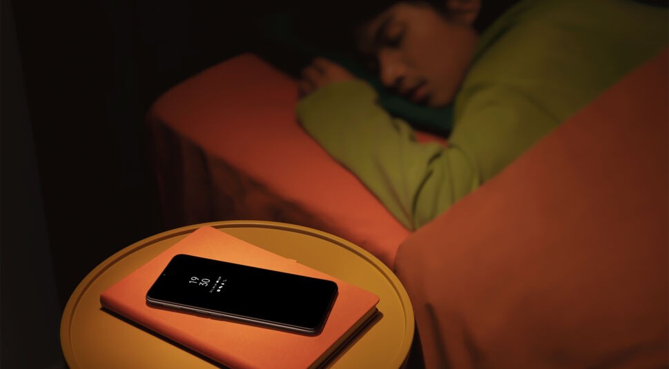 Ein Junge schläft, auf dem Nachttisch liegt ein Oppo A16s im Standby-Modus.