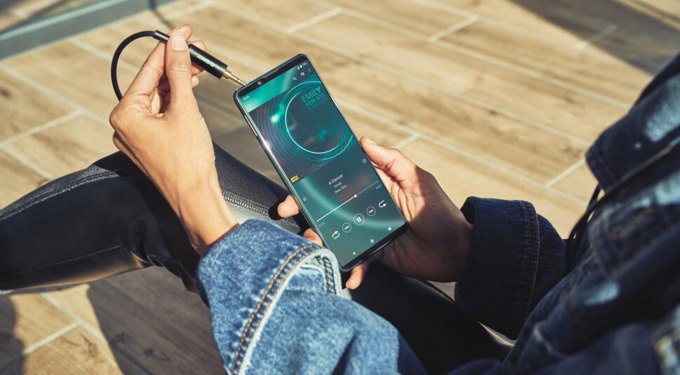 Eine Frau steckt ihre Kopfhörer in den Anschluss des Sony Xperia 5 III 5G.