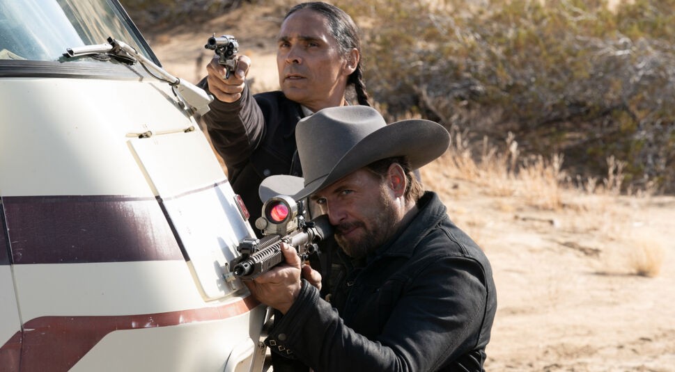 Zwei Männer im Film "The Forever Purge" verstecken sich hinter einem Fahrzeug und zielen mit Waffen auf ein Ziel.