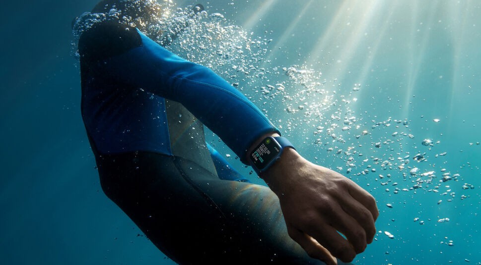 Person mit Neoprenanzug trägt die Apple Watch 7 unter Wasser
