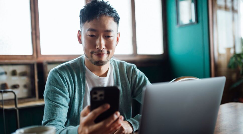 Mann nutzt Smartphone und Computer