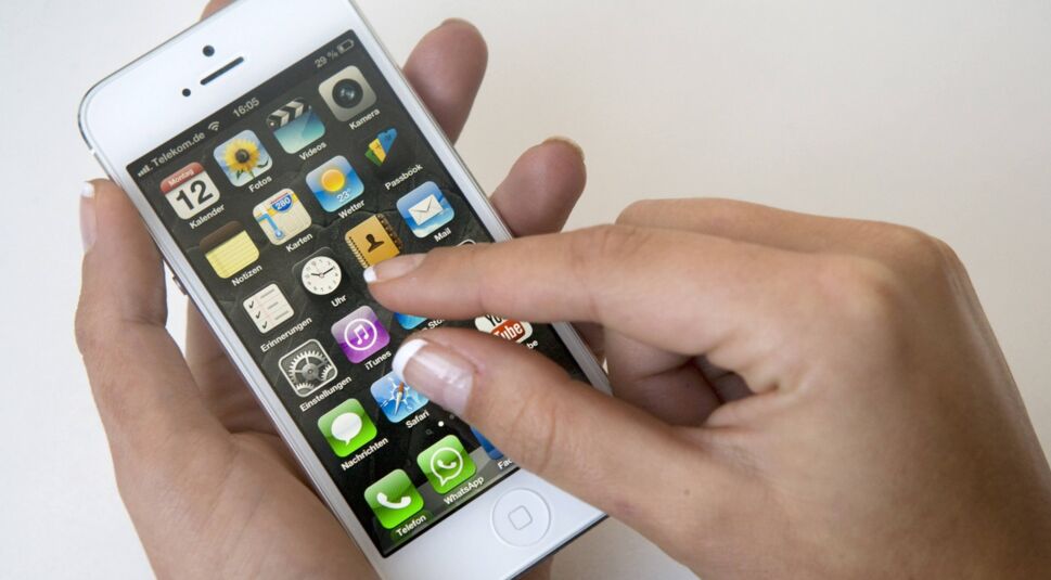 Frauenhand tippt auf Display des iPhone 5