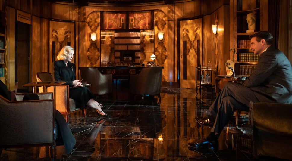 Cate Blanchett und Bradley Cooper sitzen sich in einem prunkvollem Raum gegenüber