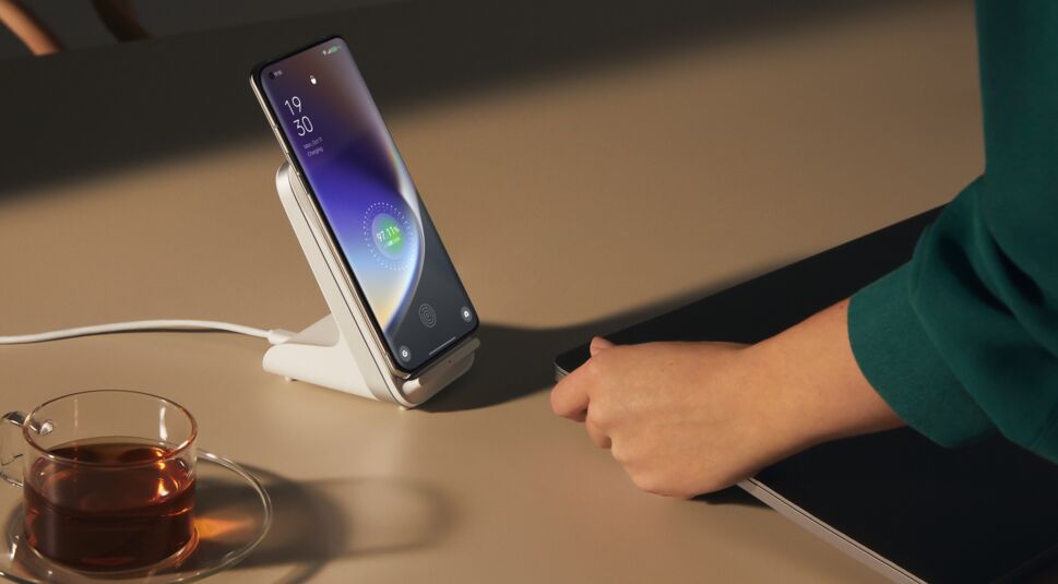 Smartphone OPPO Find X5 Pro steht auf Tisch in Ladegerät, im Vordergrund volle Teetasse