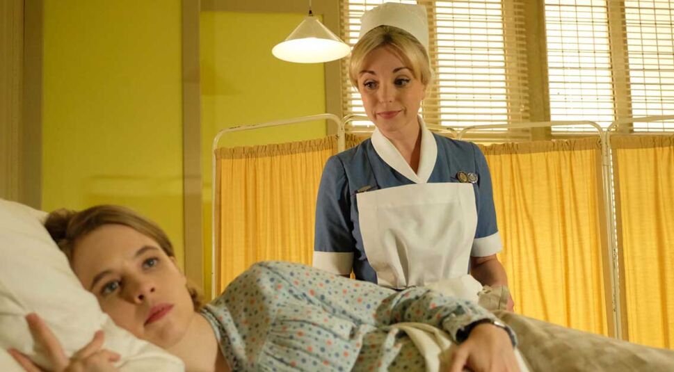 Eine Hebamme sitzt am Bett einer Patientin in der Serie Call the Midwife