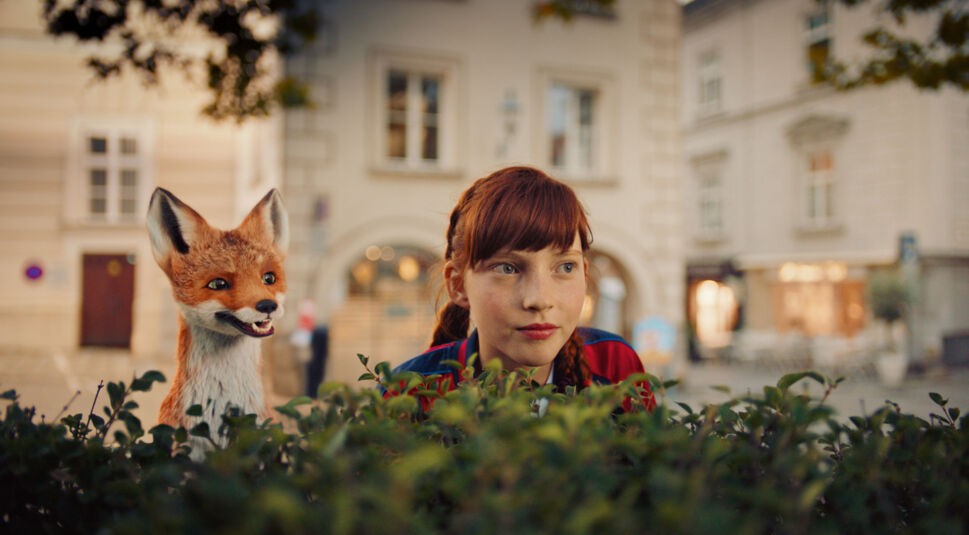 Ida (Emilia Maier) und ihr Fuchs schauen über eine Hecke im Film Die Schule der magischen Tiere