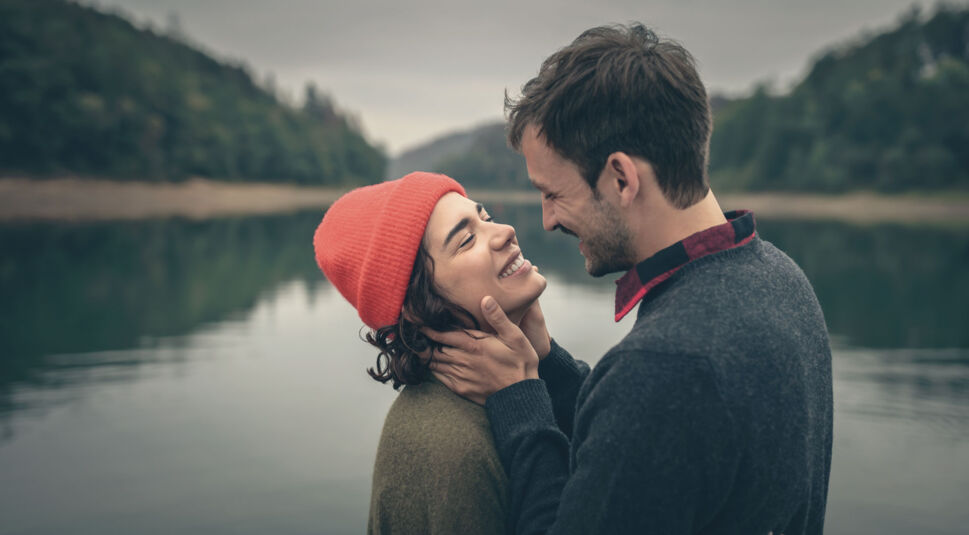 Ein Paar steht an einem See im Freien und schaut sich tief in die Augen