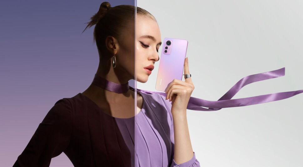 Frau in violettem Kleid hält das Smartphone Xiaomi 12 Lite 5G neben ihren Kopf