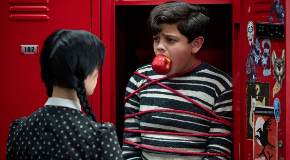 Wednesday (Jenna Ortega) steckt ihren Bruder Pugsley (Issac Ordonez) in einen Schulspind