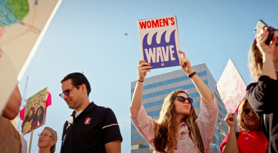 Eine Frau hält auf einem Protest ein Schild hoch 