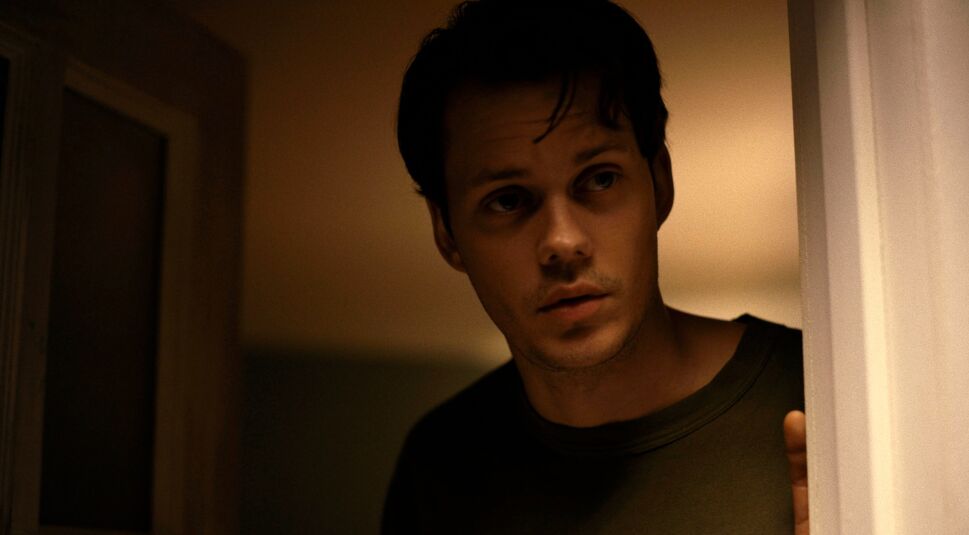 Ein junger Mann öffnet eine Haustür.