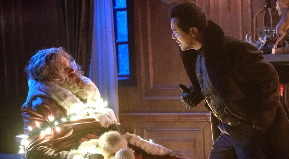 David Harbour als Weihnachtsmann mit einer Lichterkette an einem Stuhl gefesselt