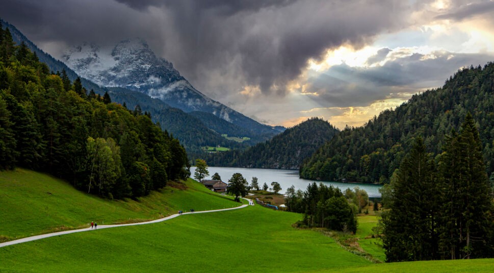 Ein See zwischen hohen Bergen, im Hintergrung ein Sonnenuntergang
