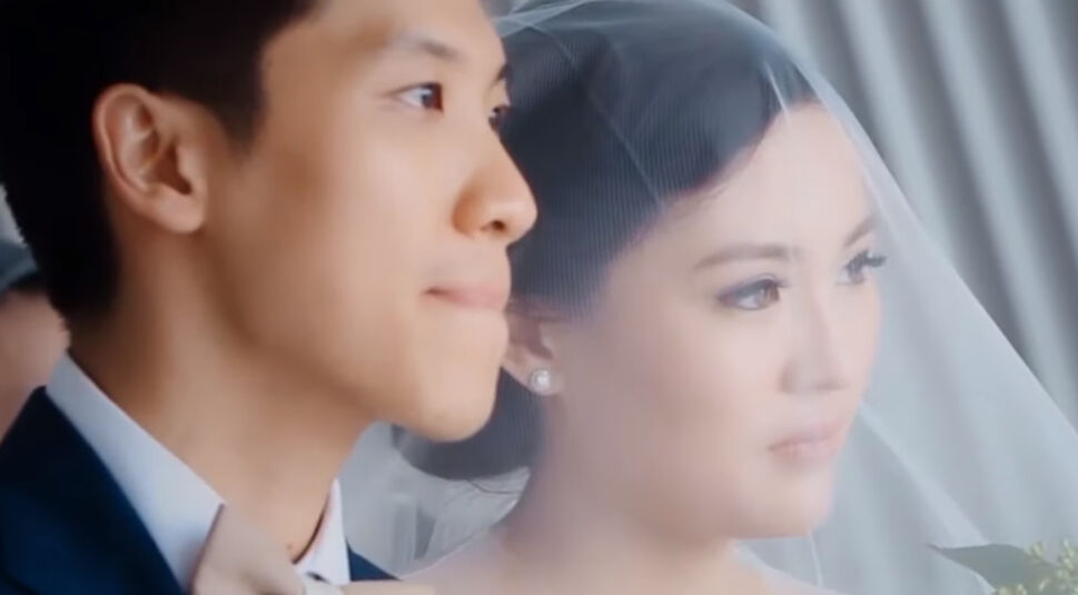 Braut und Bräutigam stehen in Anzug und Hochzeitskleid nebeneinander und blicken in die Ferne.