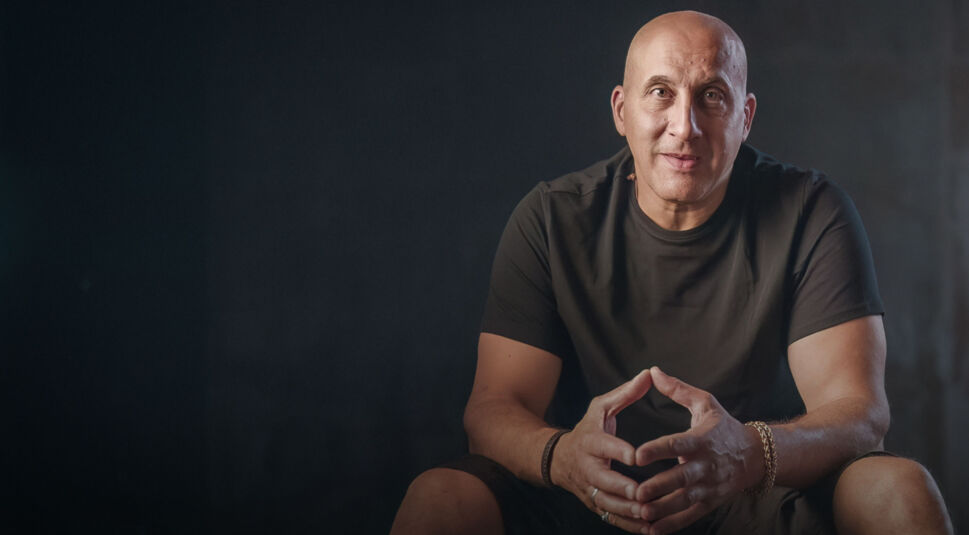 Der als „Der Spiderman von Paris“ bekannte glatzköpfige Vjeran Tomic sitzt mit gefalteten Händen auf einem Hocker.