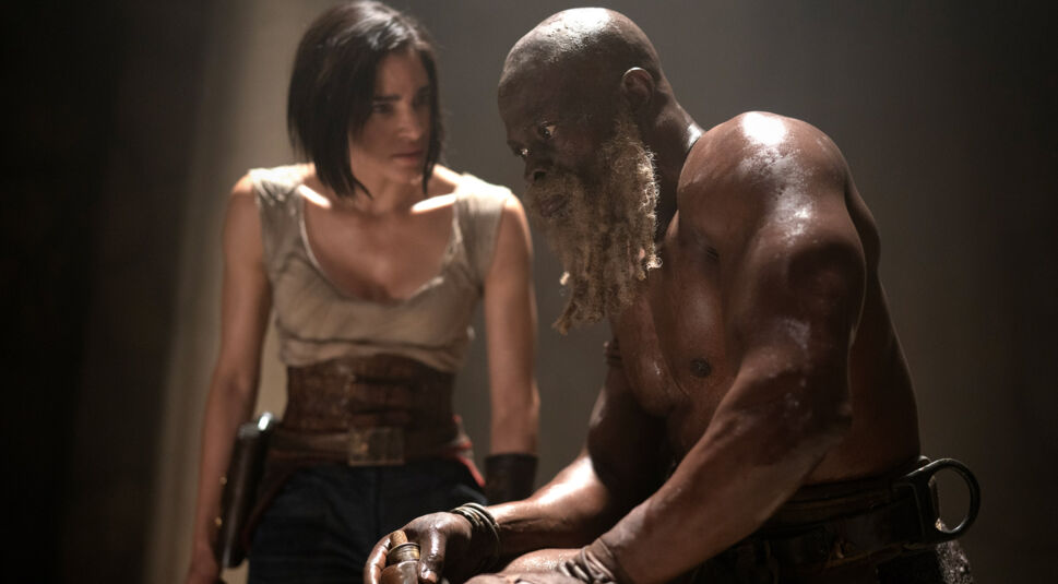 General Titus (Djimon Hounsou) ist mit freiem Oberkörper gefesselt und schaut erstarrt nach vorn.