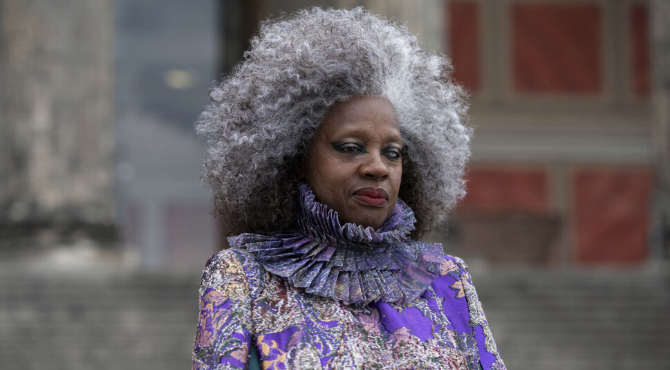 Dr. Volumnia Gaul (Viola Davis) trägt ein auffälliges lilanes Kostüm und schaut böse