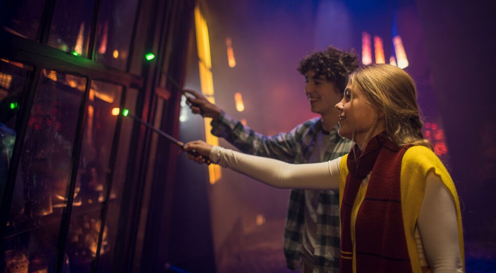 Zwei junge Menschen halten Zauberstäbe in die Luft