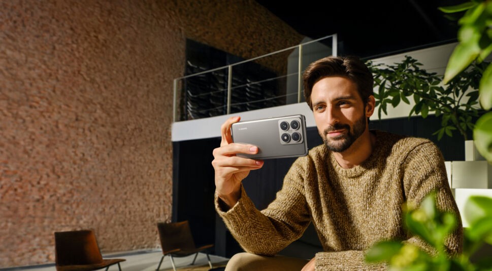 Junger Mann sitzt auf der Couch und schaut auf sein Xiaomi 14T Pro