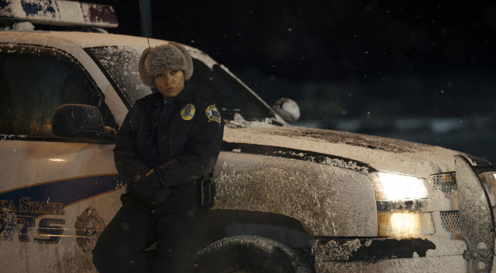 Kali Reis lehnt als Polizistin am verschneiten Auto