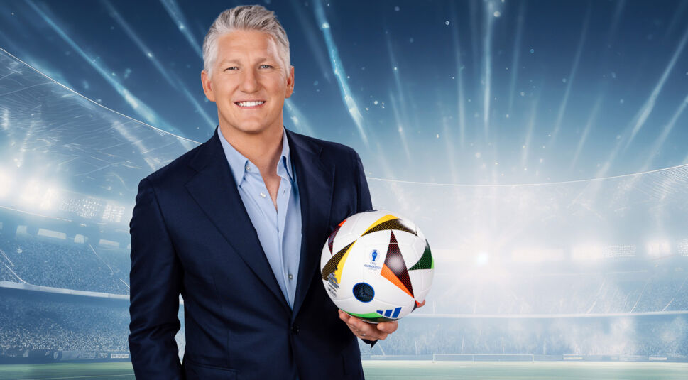 Sebastian Schweinsteiger hält ein Fußball in die Kamera und lächelt