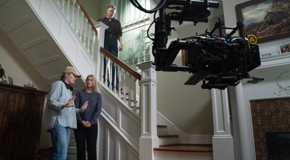 Hinter den Kulissen von Five Nights at Freddy’s 2 gibt Regisseurin Emma Tammi einer Schauspielerin Anweisungen am Set eines Hauses mit Treppenaufgang.