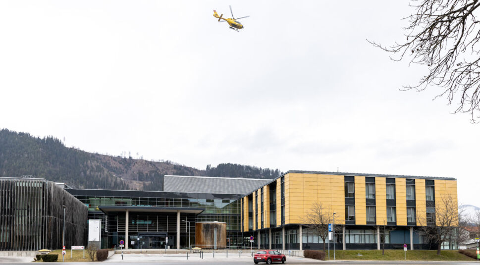 Ein gelber Hubschrauber fliegt über einem Krankenhaus.