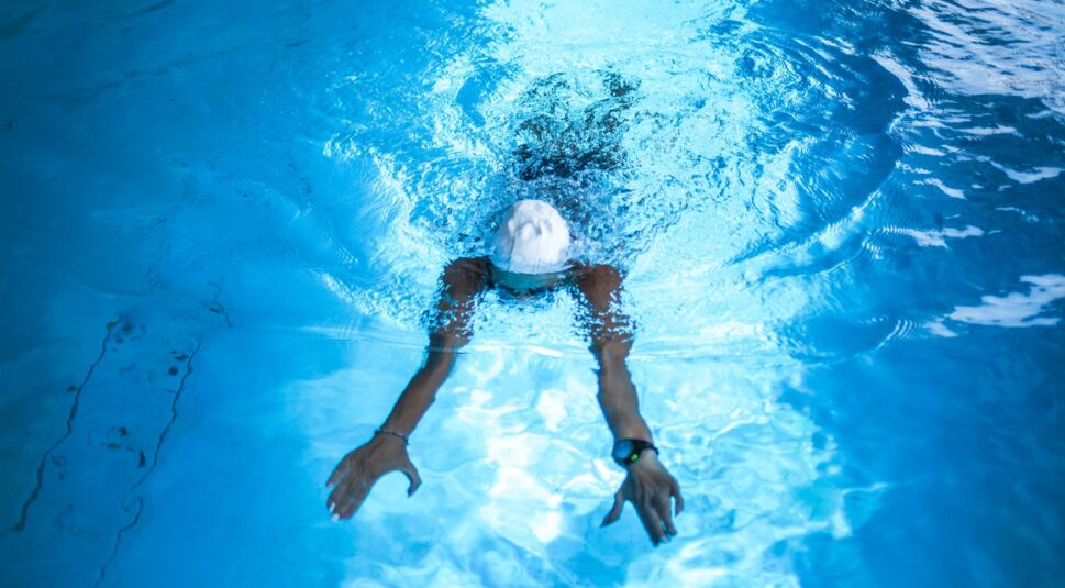 Person schwimmt mit ihrer Smartwatch im Pool