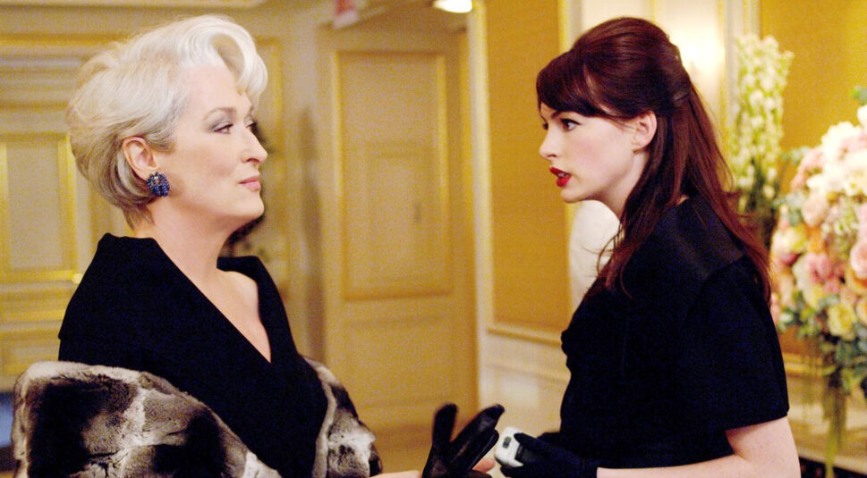 Auf dem Bild zum möglichen Film Der Teufel trägt Prada 2 sind Meryl Streep als Miranda Priestly und Anne Hathaway als Andy Sachs zu sehen. In einer eleganten Umgebung stehen sich die beiden Charaktere gegenüber. Miranda blickt kühl und überlegen, während Andy ernsthaft und entschlossen wirkt. Die Szene vermittelt Spannung und Stilbewusstsein.