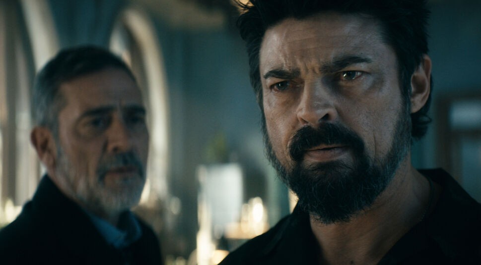 Auf dem Bild zum The Boys Staffel 5 Ausblick siehst Du zwei Männer in einer scheinbar ernsten oder konfrontativen Szene. Der Mann rechts, mit dunklem, vollem Bart und intensivem Blick, ist Butcher, dargestellt von Karl Urban. Links steht Joe Kessler, gespielt von Jeffrey Dean Morgan, in einer dunklen Jacke und mit einem ernsten Gesichtsausdruck. Die Szene wirkt düster und angespannt, mit einem Hintergrund, der auf eine Innenraum-Umgebung schließen lässt.