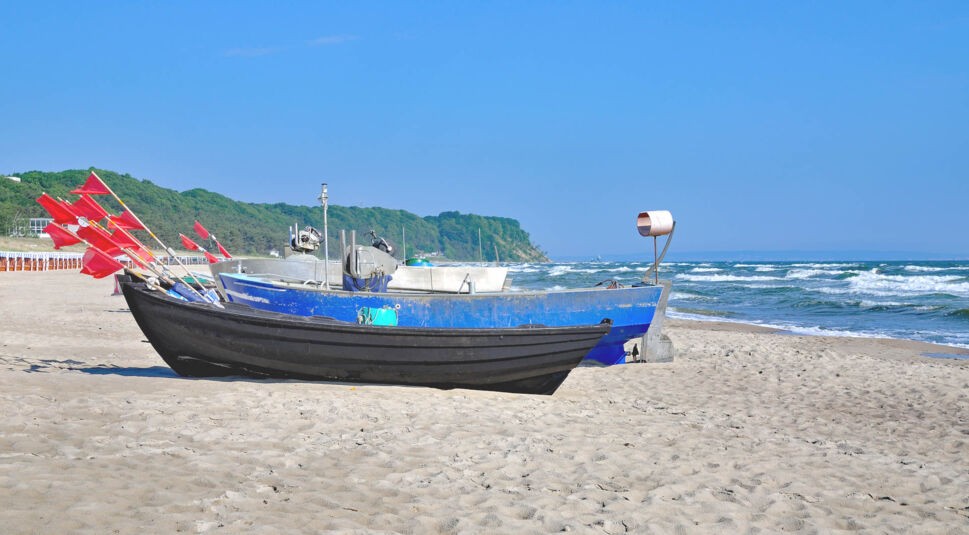 Mehrere Boote mit roten Fahnen stehen an einem Strand