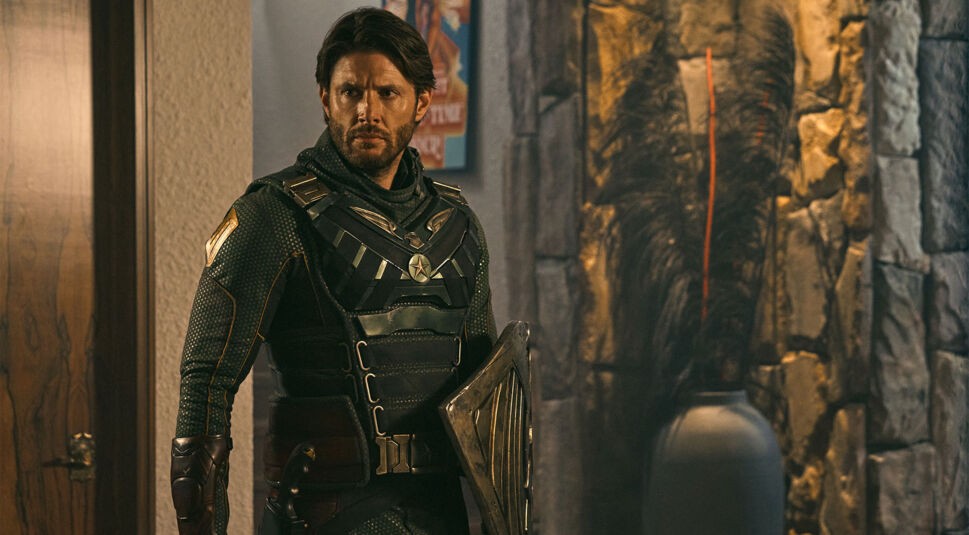 Auf dem Bild zu der Spin-off-Serie Vought Rising ist Soldier Boy zu sehen. Er steht in einem Raum und hält sein Schild in der linken Hand.