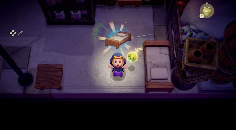 Auf dem Bild zum Test von "The Legend of Zelda: Echoes of Wisdom" steht Zelda freudig mit erhobenen Armen in einem kleinen Raum. Neben ihr schwebt ein leuchtendes, gelbes Wesen. Über Zelda erscheint ein schwebendes Bett, das von farbigen Lichtstrahlen umgeben ist. Die Umgebung zeigt einfache Möbel und Vorratskisten, während ein Topf in der Ecke hervorgehoben wird. Die Szene wirkt hell und spielerisch, mit einem Hauch von Magie.