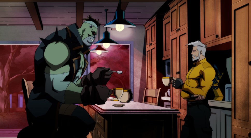 In einer Szene aus Creature Commandos sitzen Frankenstein und Rick Flag Sr. entspannt in einer Küche. Frankenstein, groß und muskulös mit grünlicher Haut, hält einen Löffel und schaut lächelnd zu Rick Flag Sr., der in einem gelben Oberteil eine Tasse hält. Die Szene wirkt ruhig, mit warmem Licht und dunklen Holzmöbeln im Hintergrund.