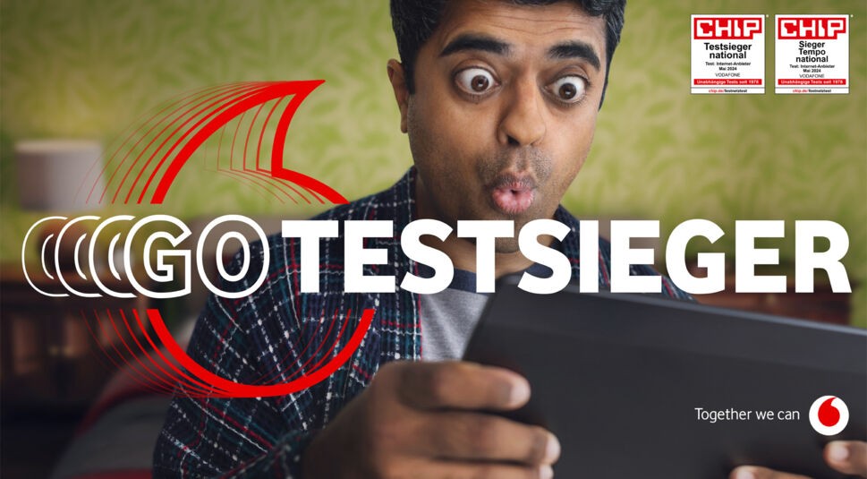 Im Bild des GoTestsieger-Artikels blickt ein überraschter Mann mit weit geöffneten Augen auf ein Tablet vor einem grünen, gemusterten Hintergrund. Großer, weißer Text über dem Bild zeigt „GoTestsieger“. Oben rechts sind zwei CHIP-Auszeichnungen zu sehen, die Vodafone als führenden Internetanbieter in Deutschland auszeichnen. Unten rechts steht der Vodafone-Slogan „Together we can“ zusammen mit dem Firmenlogo.