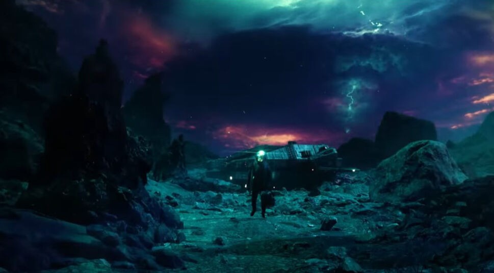 In dieser Szene aus dem Film Ash steht eine einzelne Figur vor einem abgestürzten Raumschiff in einer düsteren, außerirdischen Landschaft. Der Himmel ist von bedrohlichen, lila und grünlich leuchtenden Wolken bedeckt, aus denen Blitze zucken. Die felsige Umgebung und die dramatische Beleuchtung verleihen der Szene eine mysteriöse und unheilvolle Atmosphäre.