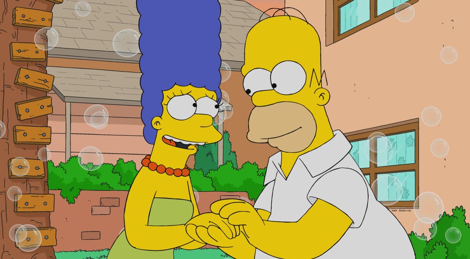 Auf dem Bild in dem Artikel über die besten Simpsons-Folgen ist zu sehen, wie Homer und Marge sich an den Händen halten. Sie stehen dabei vor einem Haus. Das Haus hat rosa Wände.
