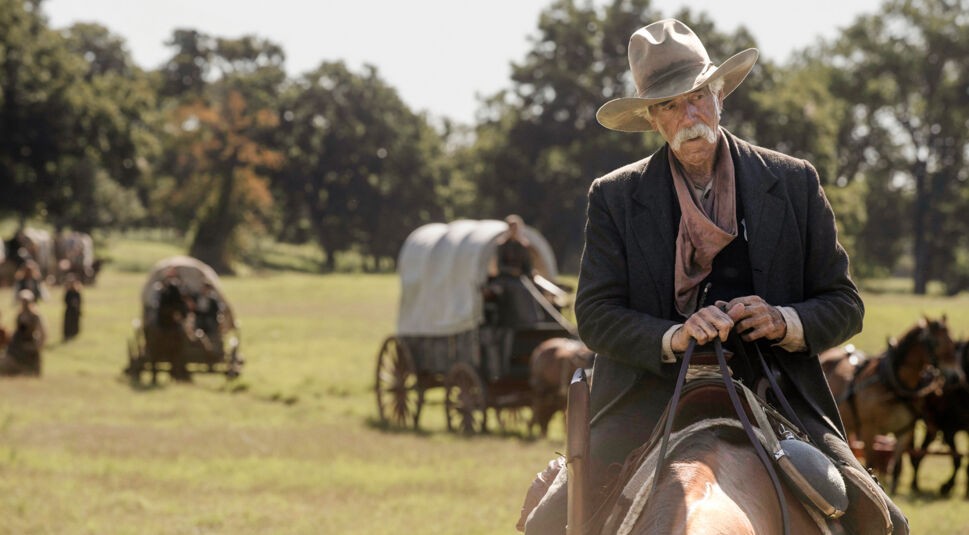Auf dem Bild in dem Artikel über die Yellowstone Reihenfolge, ist ein Mann zu sehen, der auf einem Pferd sitzt. Er trägt einen Cowboyhut. Im Hintergrund ist eine Wiese zu sehen, auf der einige Wagen fahren.